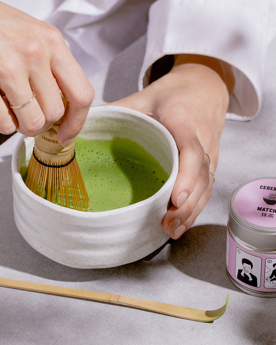 Female barista hands preparing matcha tea on a bowl, mixing it
